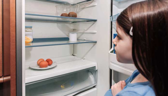 Fillette devant un réfrigérateur presque vide